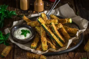 "Crispy baked zucchini fries arranged on a parchment-lined tray fresh out of the oven."